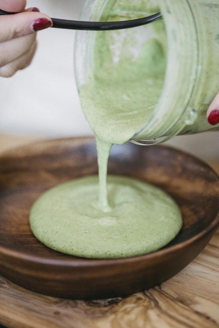 A close-up of a green smoothie being poured into a wooden bowl. Healthy lifestyle concept.